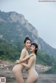 A couple of naked women standing next to each other on a beach.