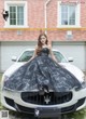 A woman in a black dress sitting on top of a white car.