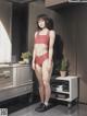 A woman in a red bikini standing in a kitchen.