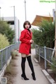 A woman in a red coat and black tights posing for a picture.
