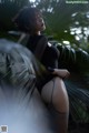 A woman in a black bodysuit and stockings posing for a picture.