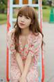 A woman in a pink dress sitting on a swing.