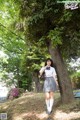 A woman in a school uniform standing next to a tree.